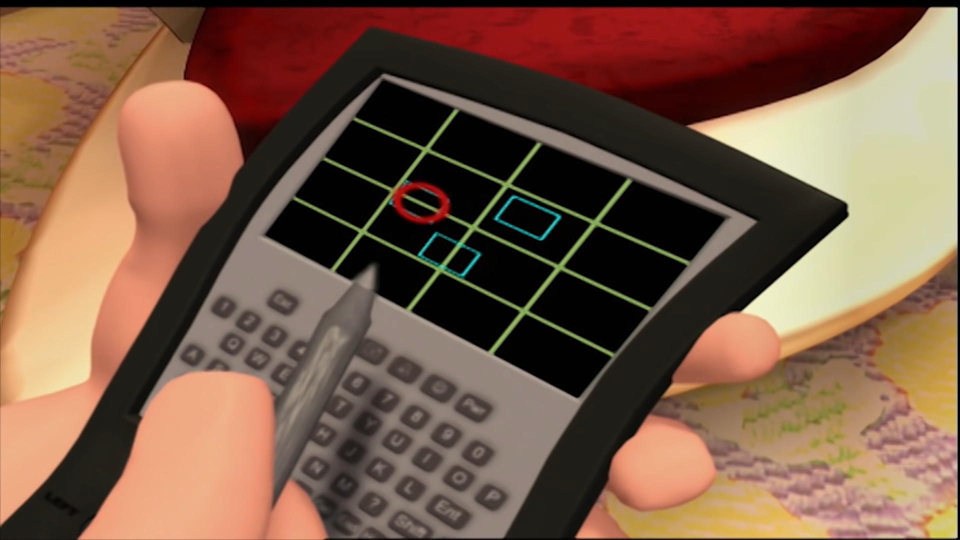 An image of a GPS device. Its screen is showing a specific location marked with a red circle, along with two teal rectangles which might be buildings.